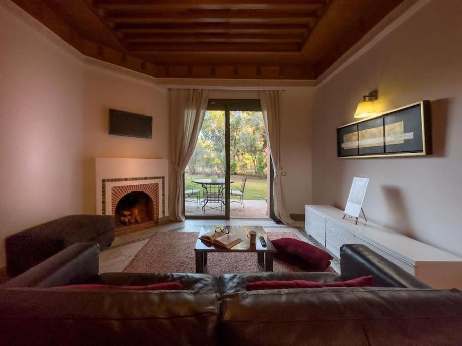 een woonkamer met een bank en een open haard bij Très joli Appart à la palmeraie coup de cœur in Marrakesh