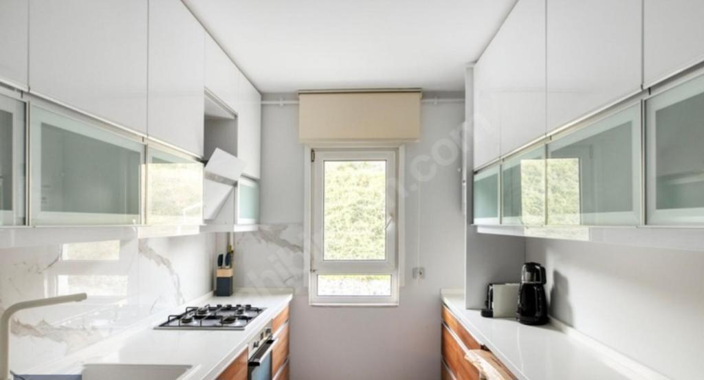 a kitchen with white cabinets and a sink and a window at Konfor home in Istanbul