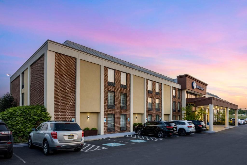 un edificio con coches estacionados en un estacionamiento en Best Western Harrisburg North Hotel en Harrisburg