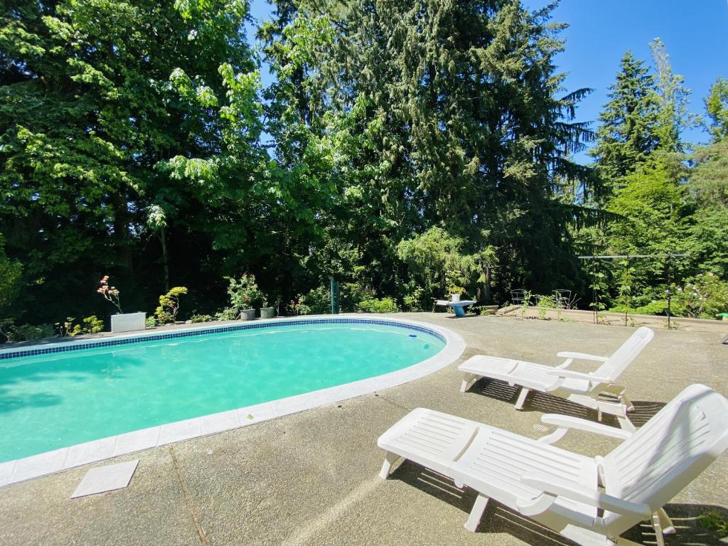 a swimming pool with two lounge chairs and a table at The Rhodo Place in Coquitlam