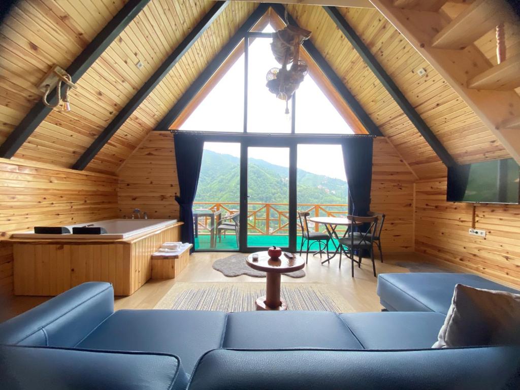 a living room with a blue couch and a large window at AFRAM BUNGALOV in Çamlıhemşin