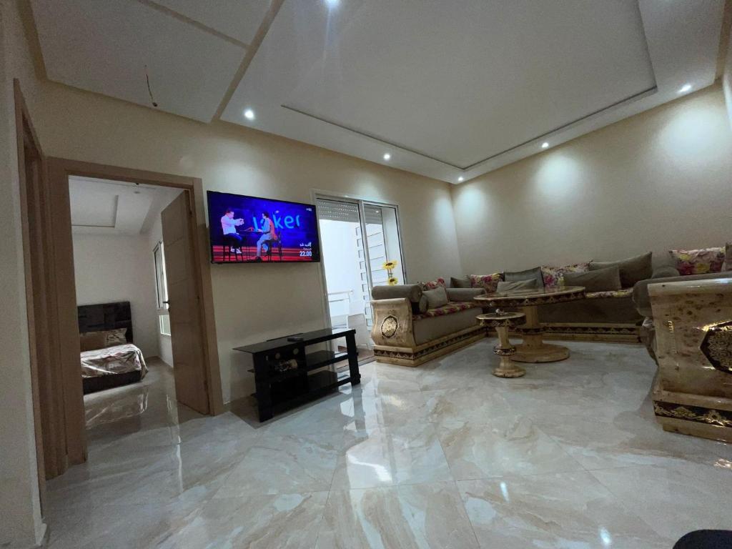 ein Wohnzimmer mit einem Sofa und einem TV an der Wand in der Unterkunft Les jardins de Bouznika in Bouznika
