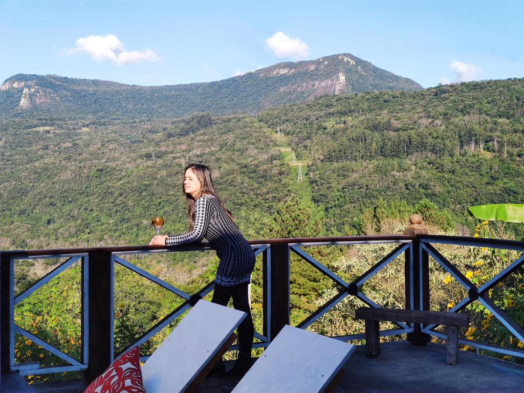 a woman standing on a balcony with mountains in the background at Casa Ortmann in Canela