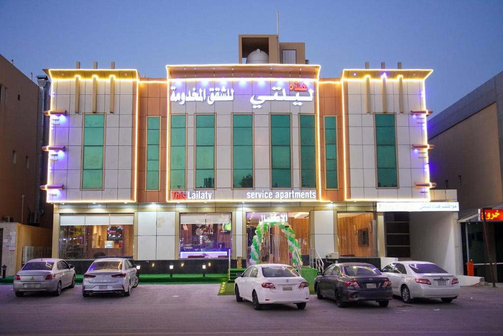 Un edificio con coches aparcados delante. en هذه ليلتي فرع النجاح باليرموك- This Lailaty Al Nagah Branch, en Riad