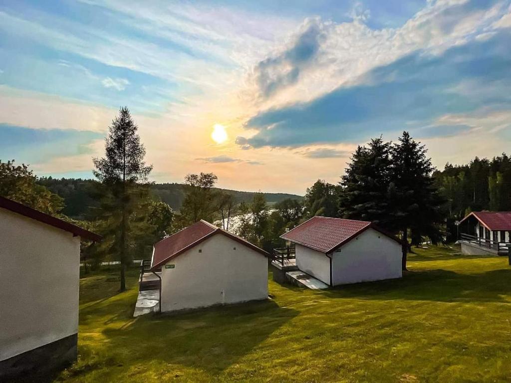 eine Gruppe von Gebäuden auf einem Feld mit der Sonne am Himmel in der Unterkunft Wypoczynek Mazurska Górka domki 2 osobowe in Stare Juchy