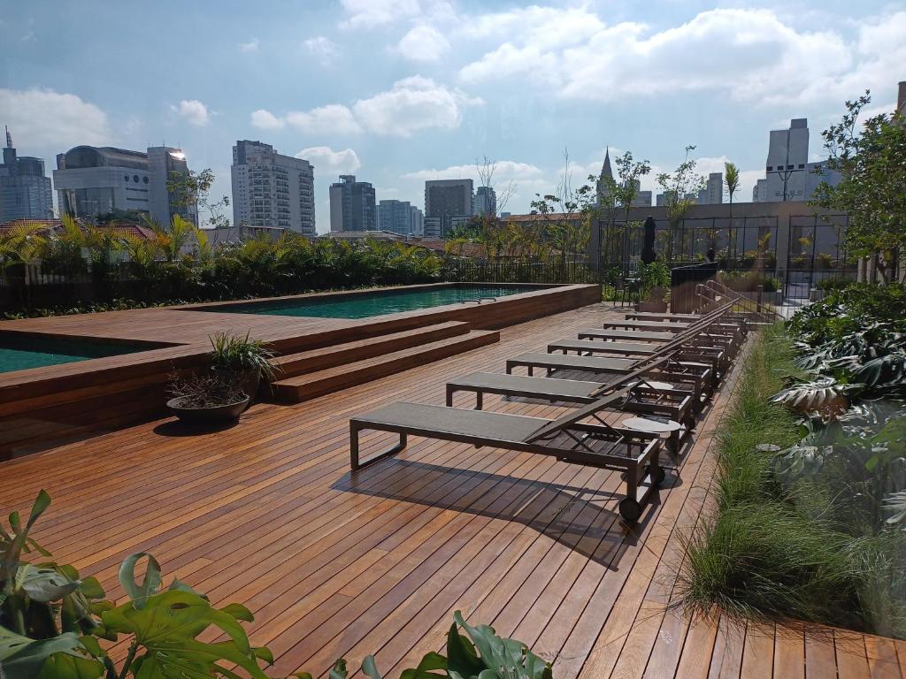 a row of benches sitting on a deck near a pool at Expand Pinheiros Linda vista e próximo ao shopping in Sao Paulo