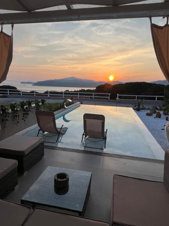 a view of a pool from a house with a sunset at Villa Messina in Capoliveri