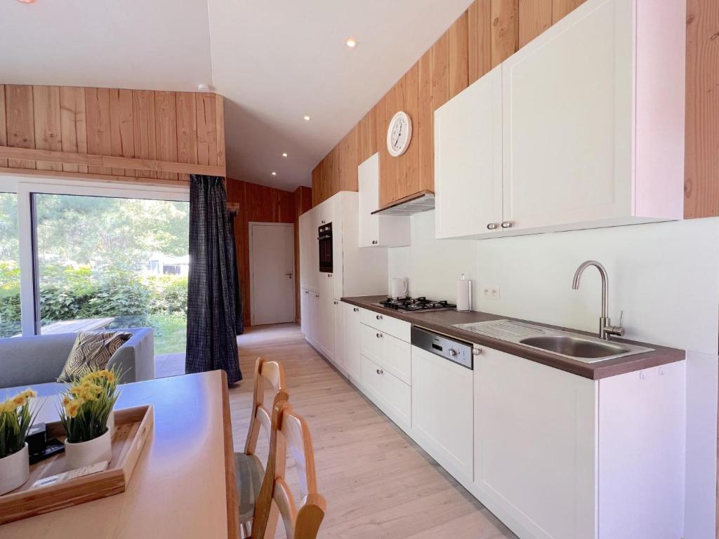 a kitchen with white cabinets and a dining table at De Goolder in Bocholt