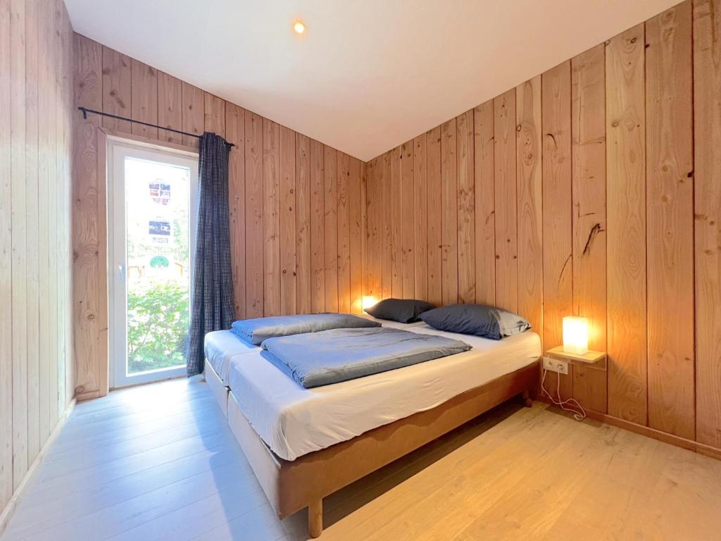 a bedroom with wooden walls and a bed with two lamps at De Goolder in Bocholt