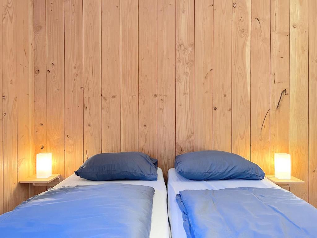 two beds in a room with wooden walls at De Goolder in Bocholt