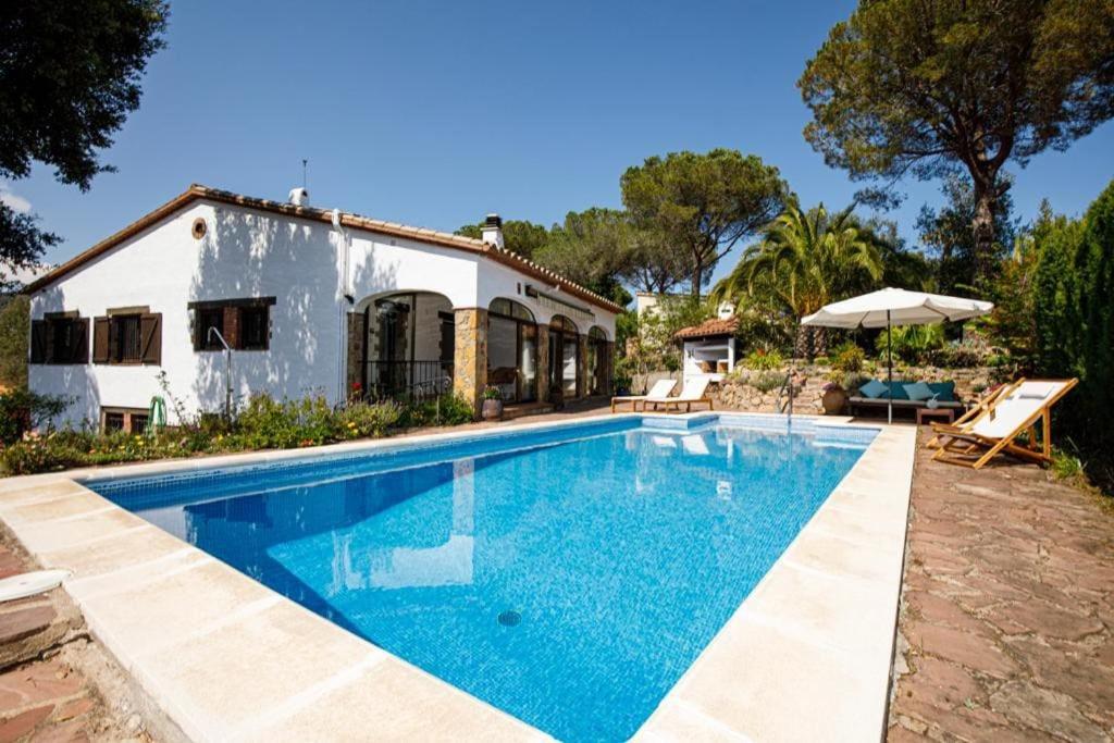 a villa with a swimming pool in front of a house at Villa en Costa Brava in Calonge