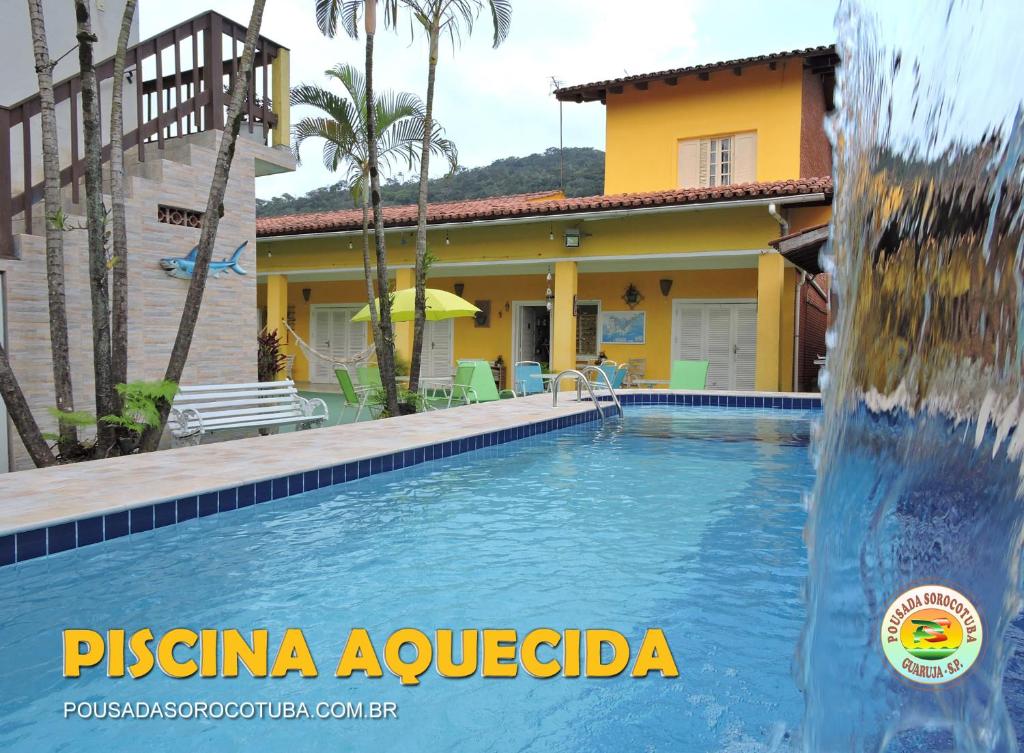 a pool with a water fountain in front of a house at Pousada Sorocotuba in Guarujá