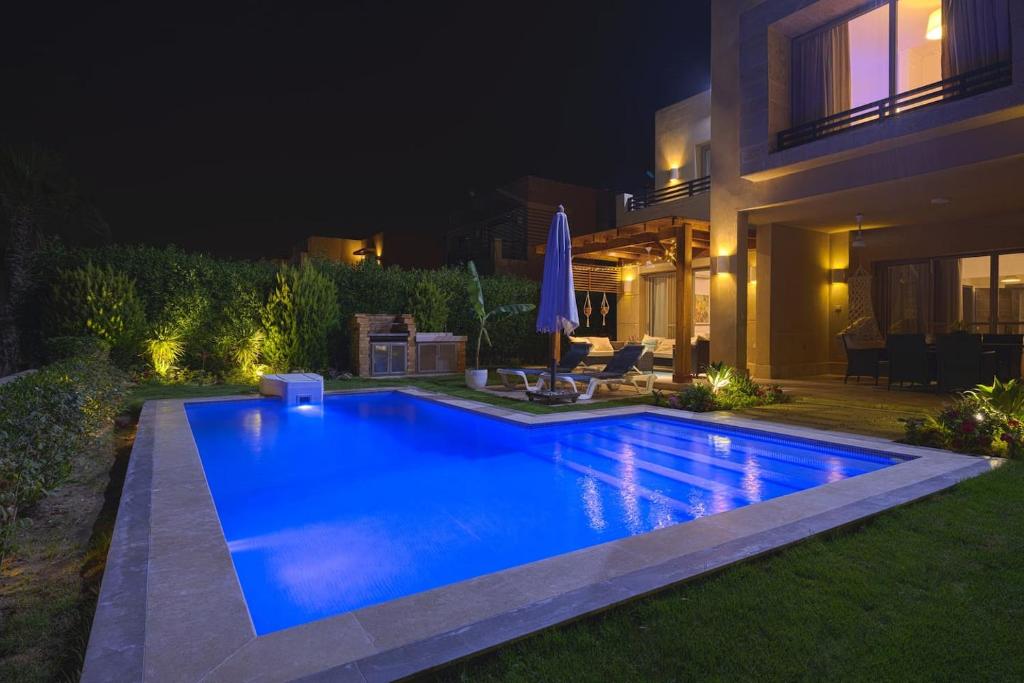 a swimming pool in front of a house at night at Safty Palm Oasis Private Pool & Beach Access in Ain Sokhna