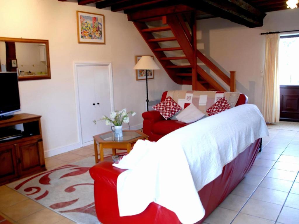 a bedroom with a large bed and a red chair at Tranquil Cottage in Normandy in Sainte-Marguerite-dʼElle