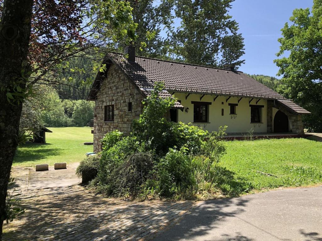 una pequeña casa de piedra en medio de un campo en Ardennes villa with riverside garden and views en Atzerath