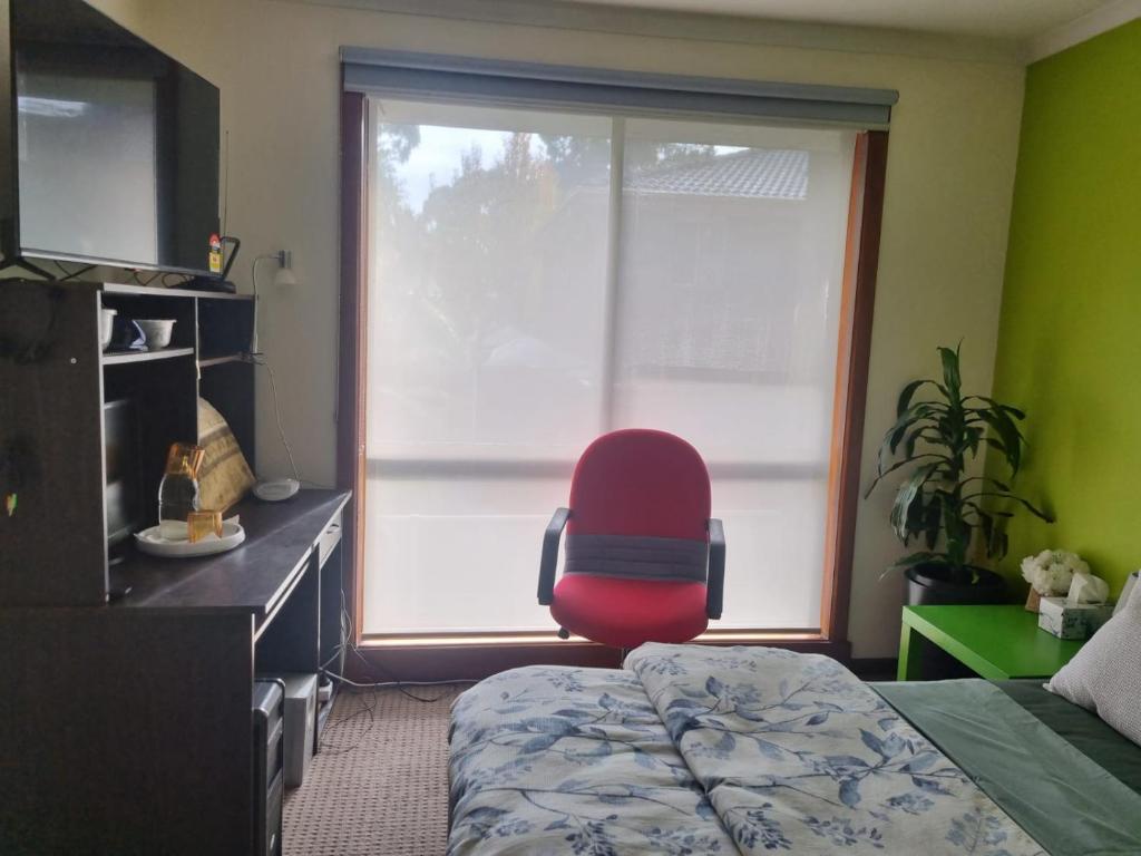 1 dormitorio con una silla roja frente a una ventana en Nava home in Rowville, en Rowville