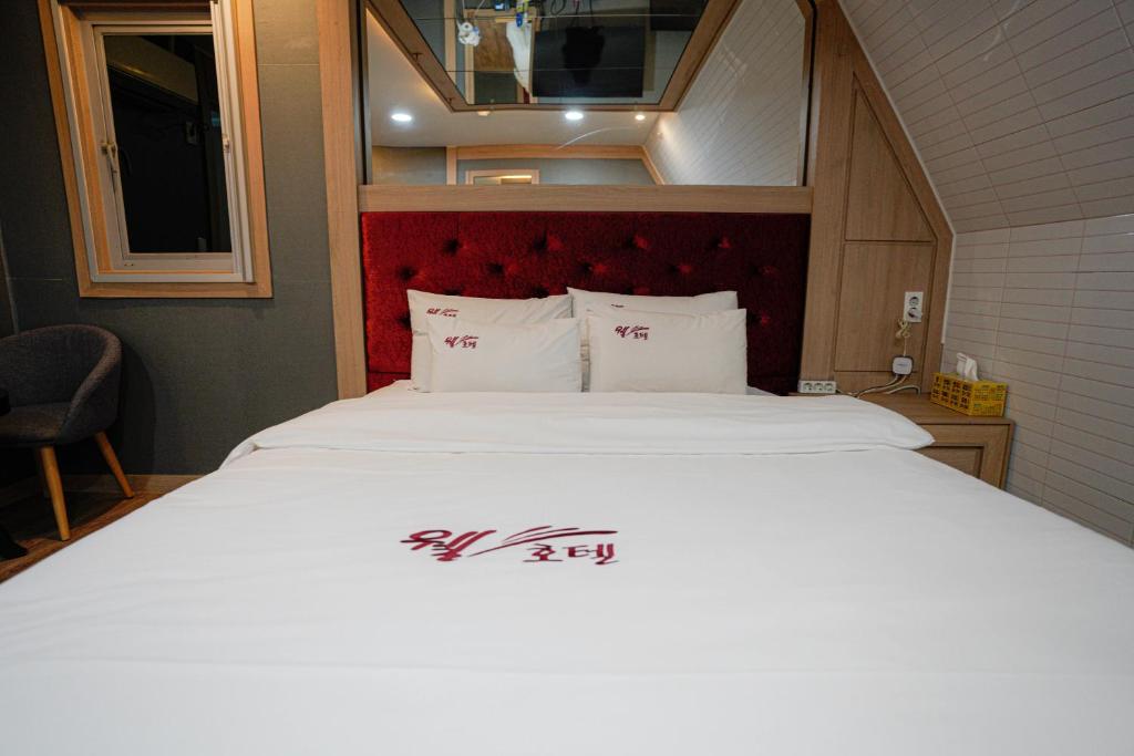 a bedroom with a large bed with a red headboard at Mokpo Well hotel in Mokpo