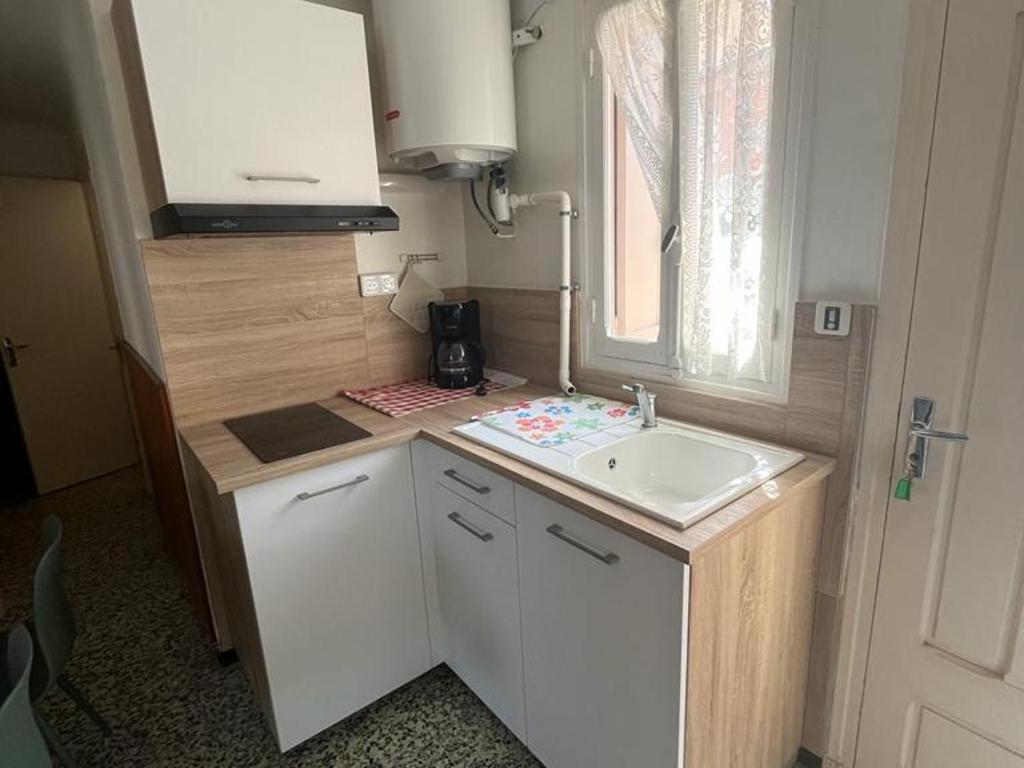 une petite cuisine avec un évier et une fenêtre dans l'établissement Maison 2 chambres à Saint-André, proche plages et Espagne, terrasse spacieuse, ménage inclus - FR-1-732-36, à Saint-André