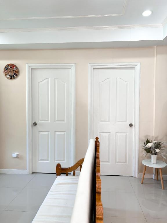 duas portas brancas num quarto branco com uma mesa em Cozy Millenium House em Baguio