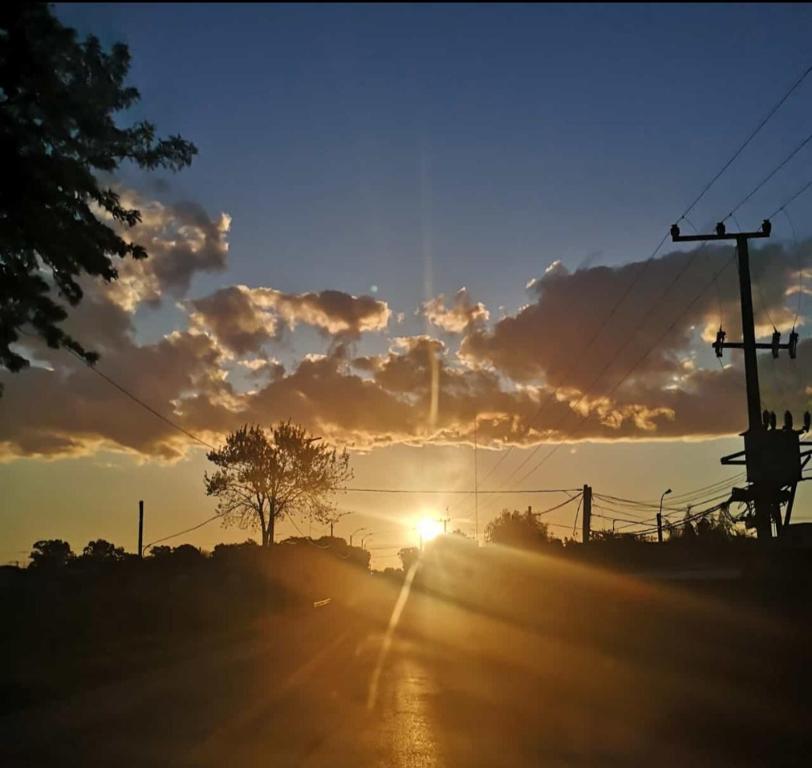 um pôr-do-sol numa estrada com o sol no céu em Barro em Villa Serrana