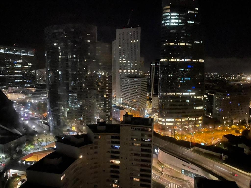 uma vista para uma cidade à noite com luzes em Grand Studio à la Défense em Courbevoie