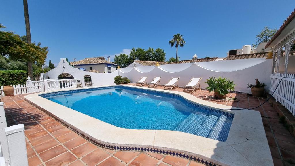 a swimming pool in a yard with chairs and a house at Villa Lucía - Benalmádena Costa in Benalmádena