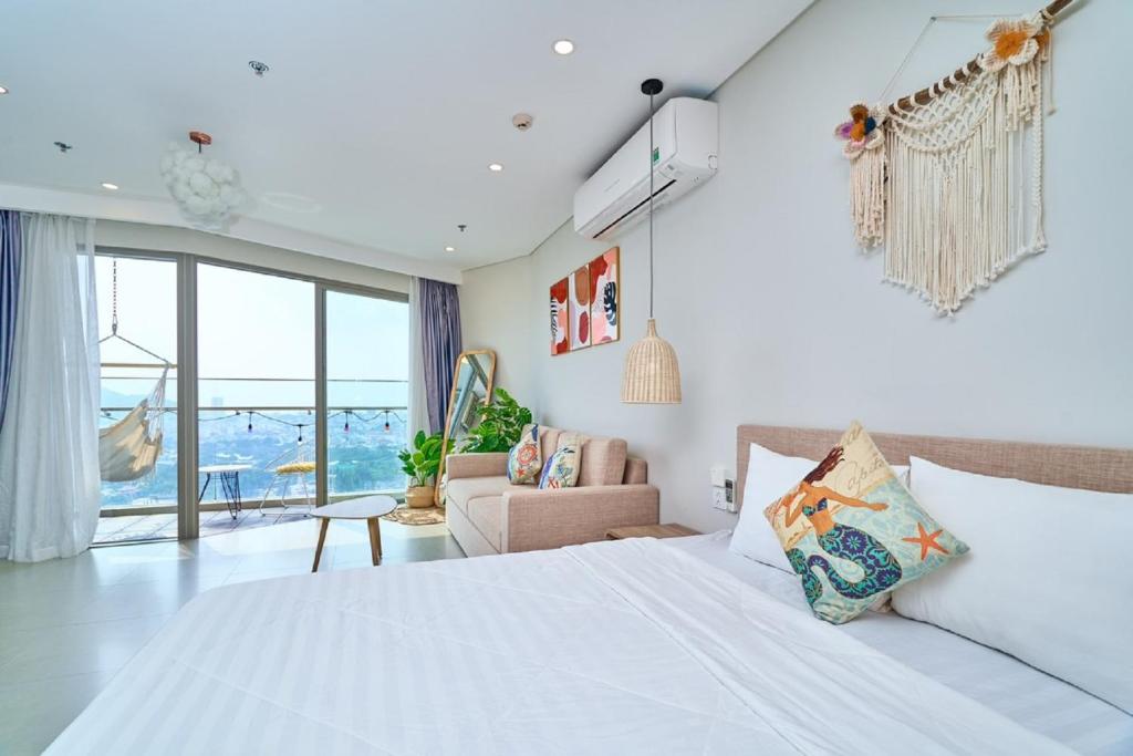 a bedroom with a white bed and a living room at The Song Vung Tau Near Beach in Vung Tau