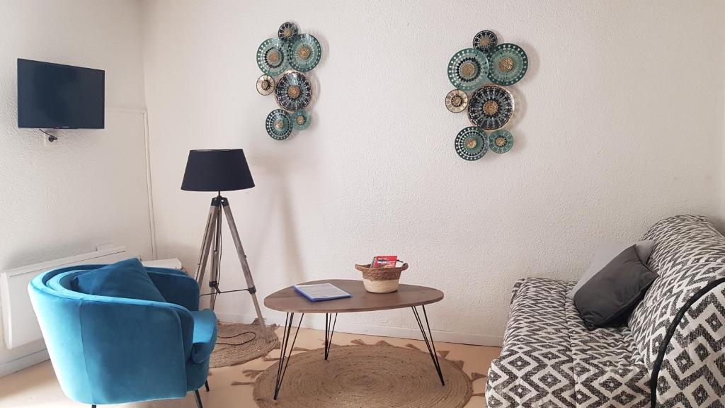 a living room with a blue chair and a table at AGREABLE APPARTEMENT in Eaux-Bonnes