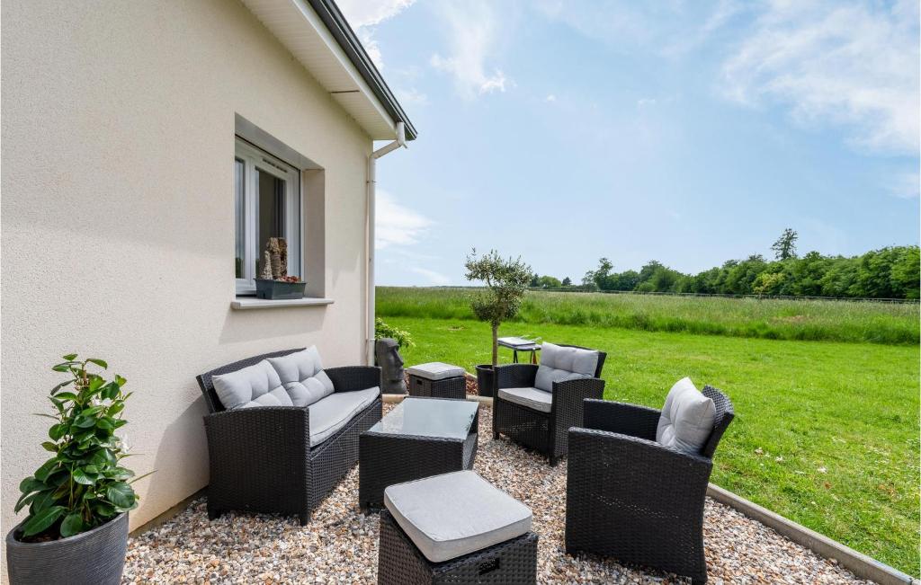 un patio con sillas, mesas y césped en Nice Home In Lyons-la-fort With House A Panoramic View, en Lyons-la-Forêt