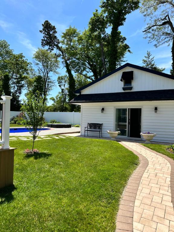 a white barn with a brick walkway in front of a yard at Unique guest house loft in Spring Lake