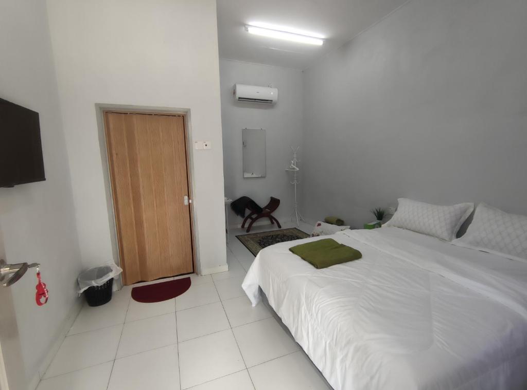 sypialnia z dużym łóżkiem i drewnianymi drzwiami w obiekcie Cahaya roomstay w mieście Kangar
