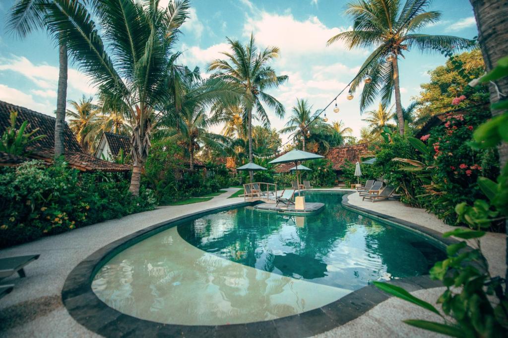 a swimming pool in a resort with palm trees at Coconut Garden Resort in Gili Trawangan