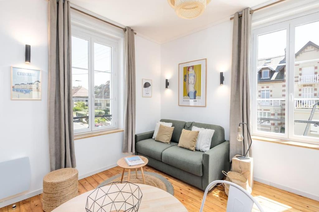 a living room with a couch and windows at Studio front de mer en centre-ville de Cabourg in Cabourg