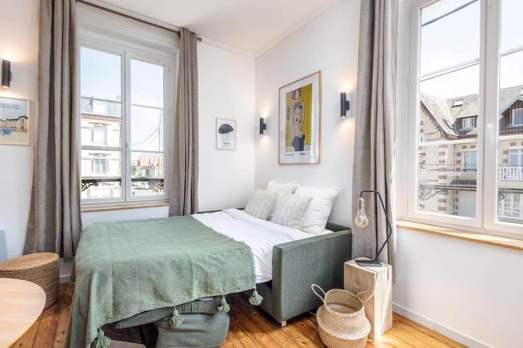 a small bedroom with a bed and two windows at Studio front de mer en centre-ville de Cabourg in Cabourg