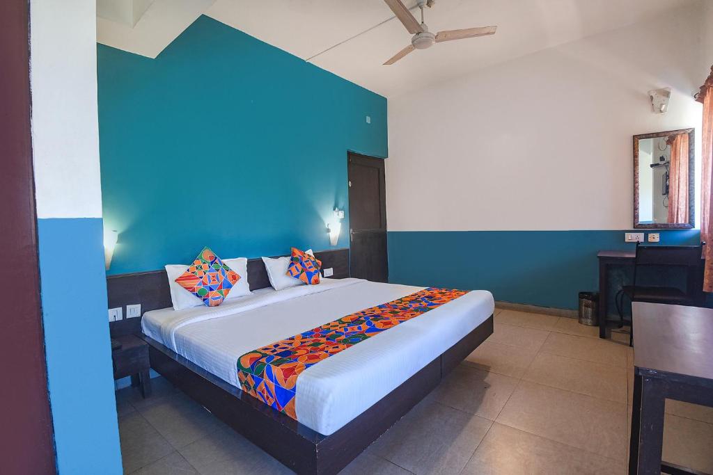 a bedroom with a large bed with a blue wall at FabExpress Paradise Inn Panaji in Old Goa