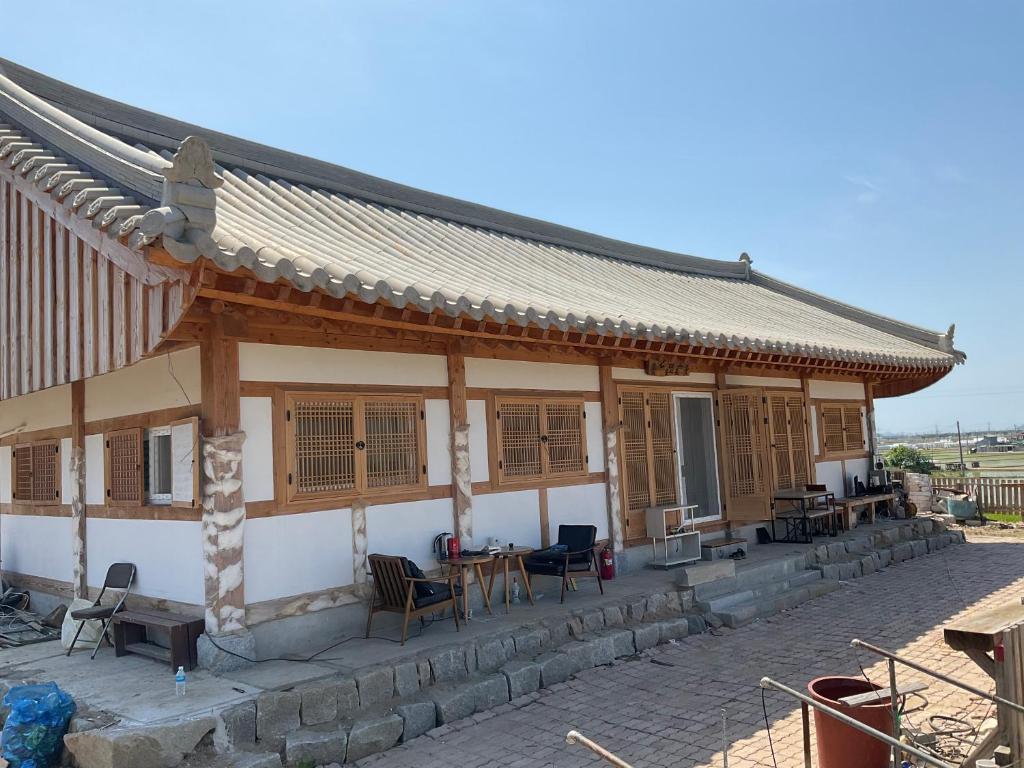 a building with a roof with chairs and tables at Guesthouse Comfort Place in Buan