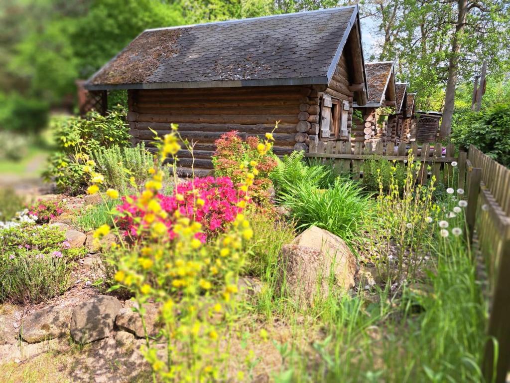 a garden with flowers in front of a cabin at Birkenhof Ashram Familien Blockhütten in Hartau