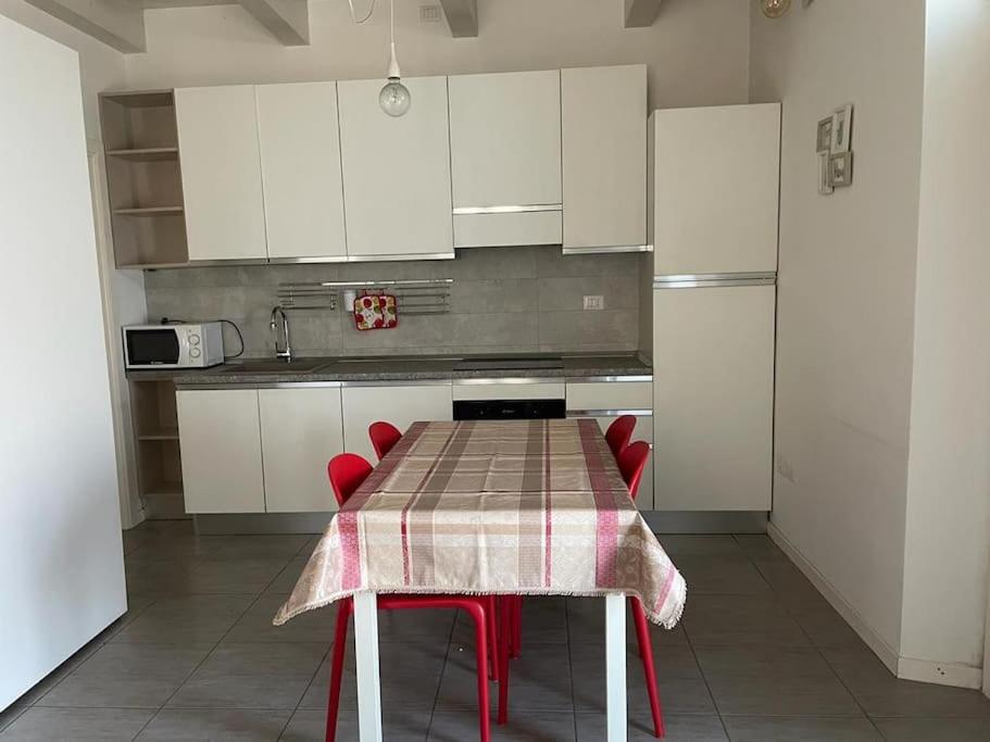 a kitchen with a table with red chairs and white cabinets at Monolocale al porto in Fano