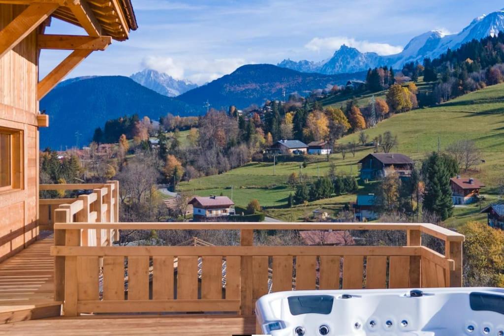 un bain à remous sur une terrasse avec des montagnes en arrière-plan dans l'établissement Chalet vue Mont Blanc avec jacuzzi extérieur, à Combloux