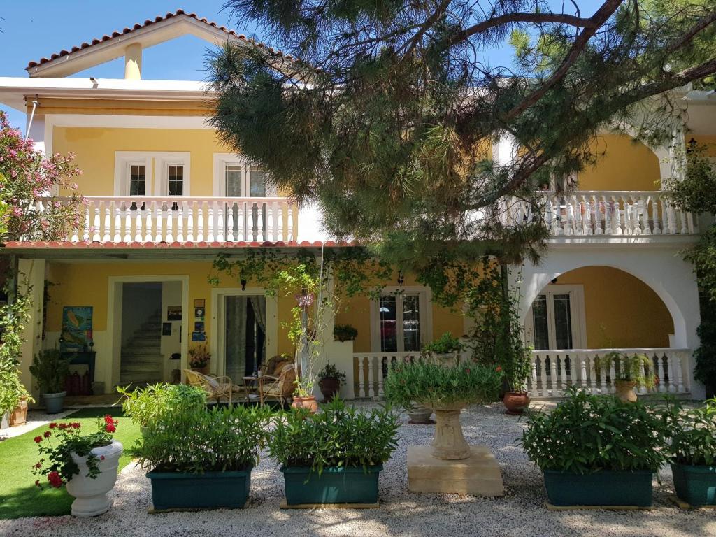 uma casa amarela com vasos de plantas em frente em Kuris Studios & Apartments em Vasilikos