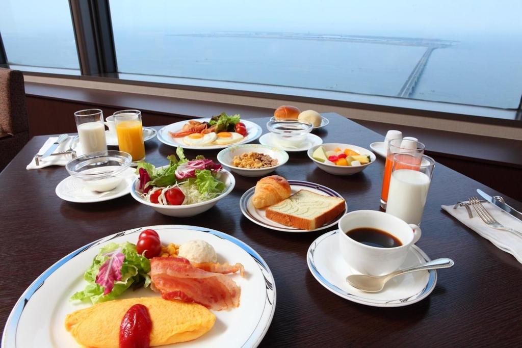 泉佐野的住宿－Odysis Suites Osaka Airport Hotel，餐桌,早餐盘和饮料