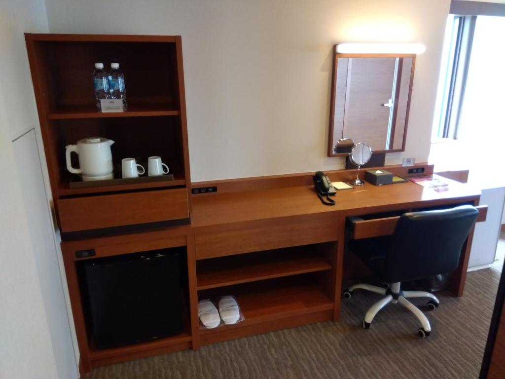 an office with a desk and a chair and a mirror at Odysis Suites Osaka Airport Hotel in Izumi-Sano
