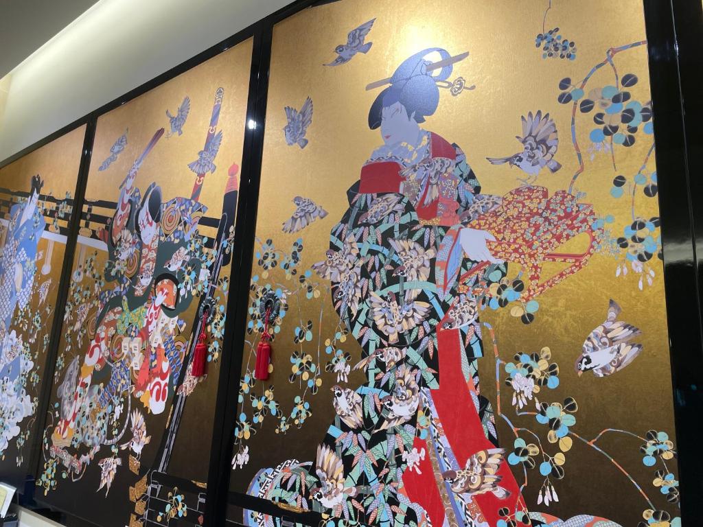 a wall with a painting of a woman in a dress at Odysis Suites Osaka Airport Hotel in Izumi-Sano