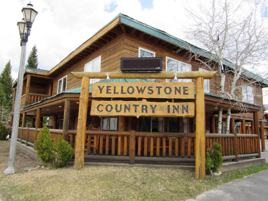 una señal de bienvenida frente a una cabaña de madera en Yellowstone Country Inn en West Yellowstone
