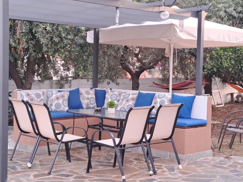 uma mesa e cadeiras sob um guarda-sol branco em Myrsini' s House em Nea Peramos