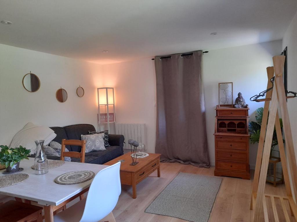 een woonkamer met een tafel en een bank bij L'atelier de la forêt in Groléjac