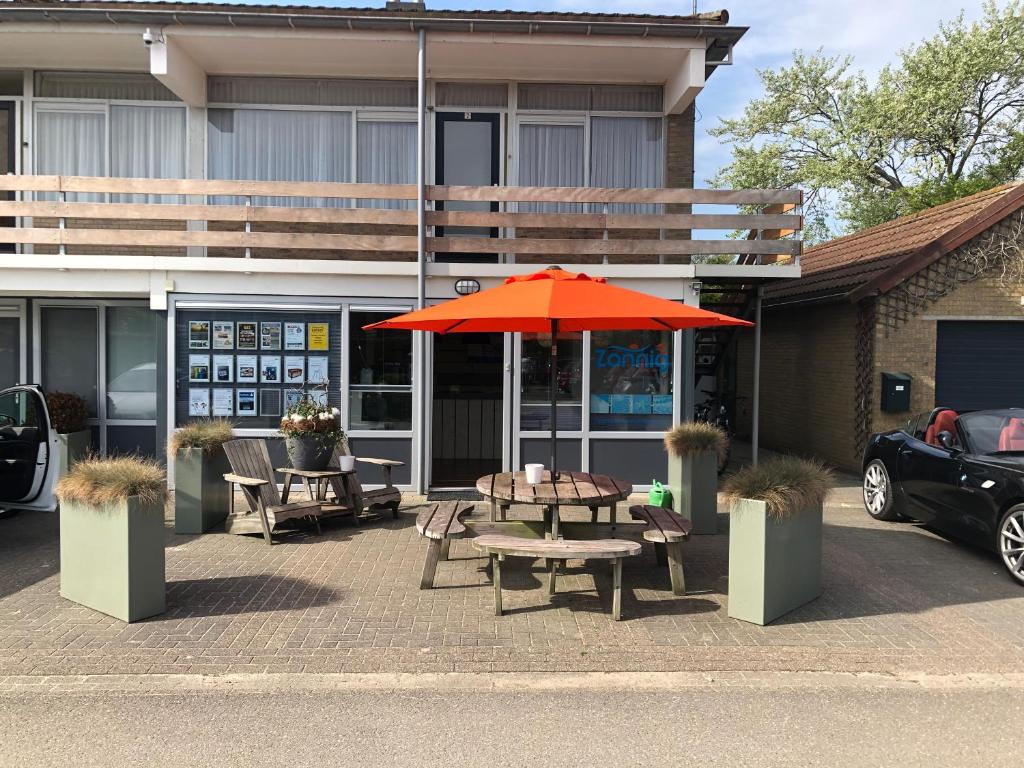 un tavolo e una panca con ombrellone di fronte a un edificio di Appartementen Zuiderstrand H a Westkapelle