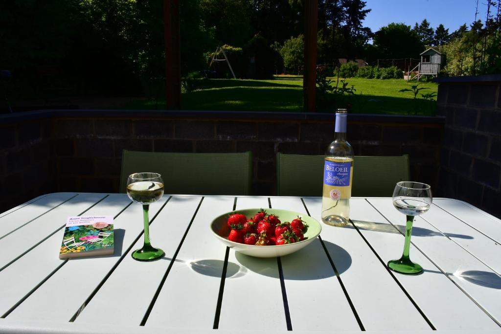 a table with a bowl of strawberries and a bottle of wine at Au four et au jardin in Namur