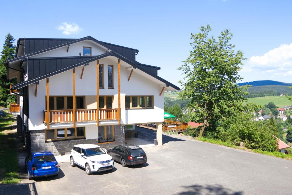a house with two cars parked in a parking lot at Wellness Apartmány Pastviny in Pastviny