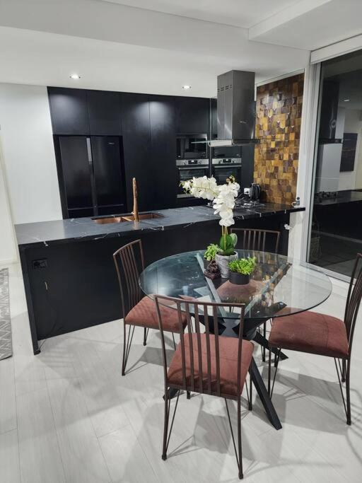 シドニーにあるBondi Junction Beautyのダイニングルーム(ガラスのテーブル、椅子付)